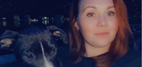 Woman and black emotional support dog in a dark setting.