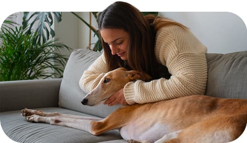 Woman lying on a couch hugging a long-nosed emotional support dog.